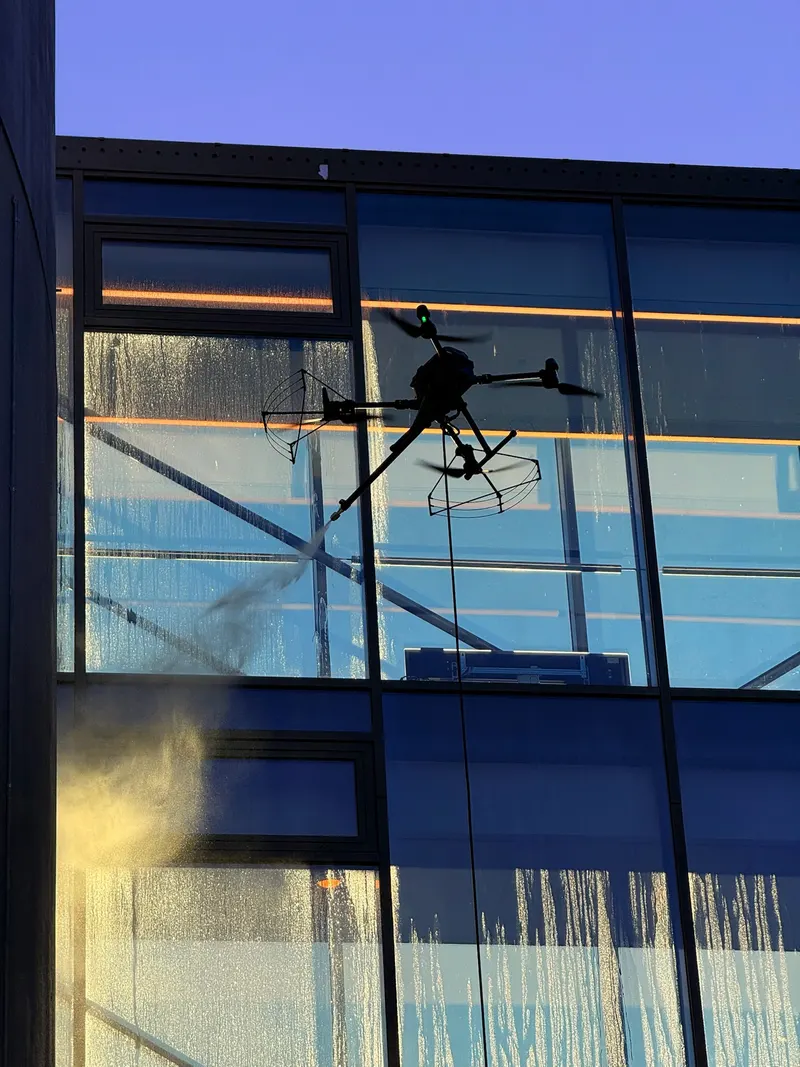 Drone tett på en glassfasade mens vannet renner nedover ruta