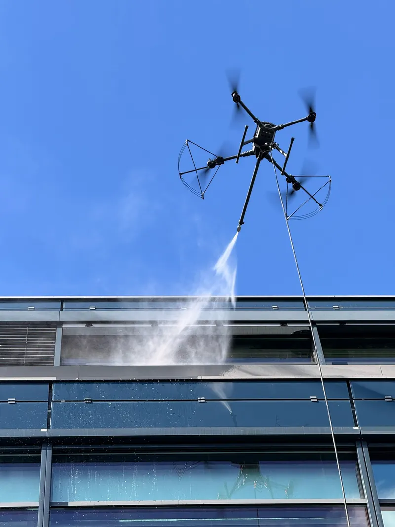 Drone som vasker øverste del av en fasade, uten stillas eller lift